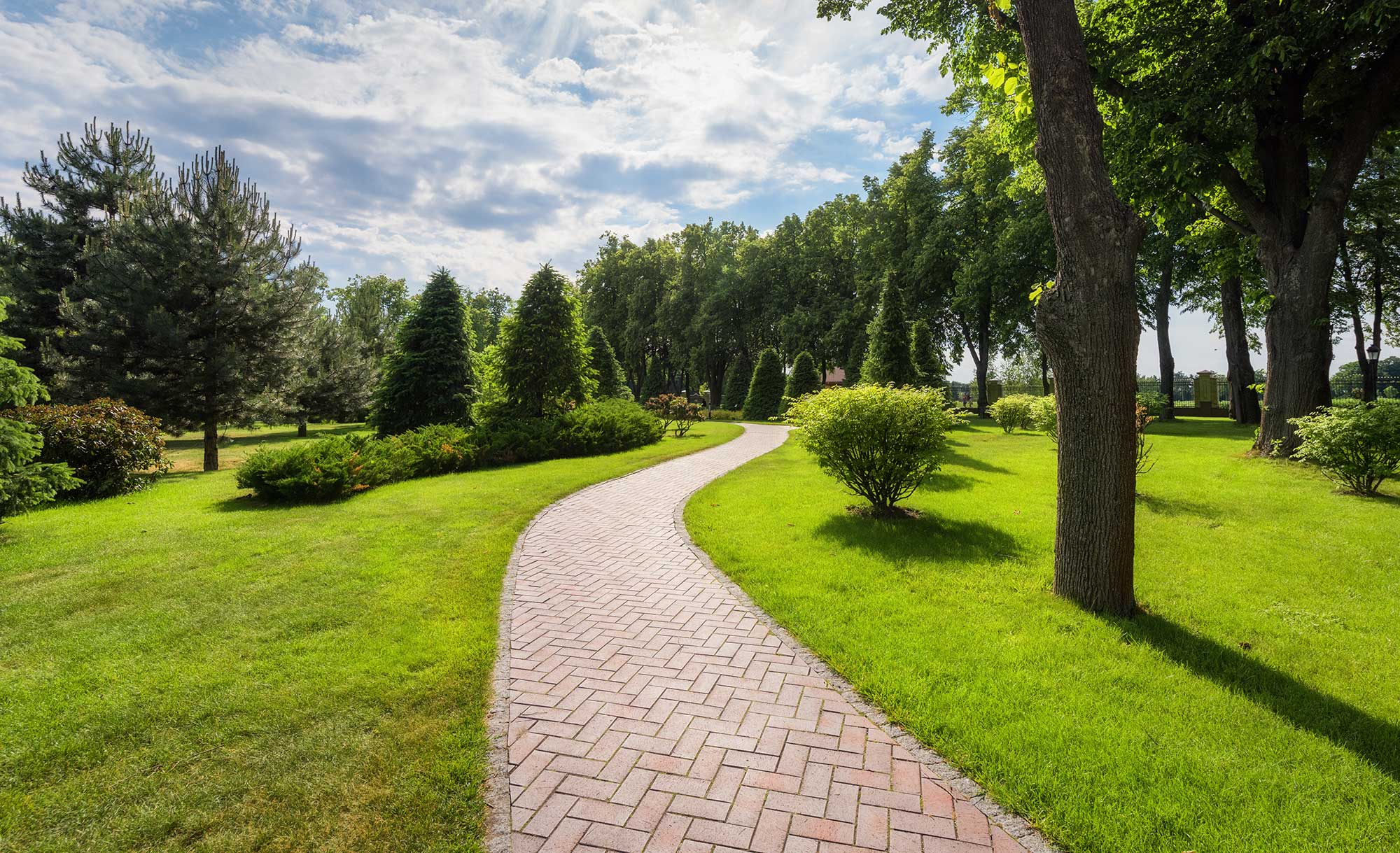 Stamped concrete walkway with herringbone brick pattern leading through a landscaped garden.